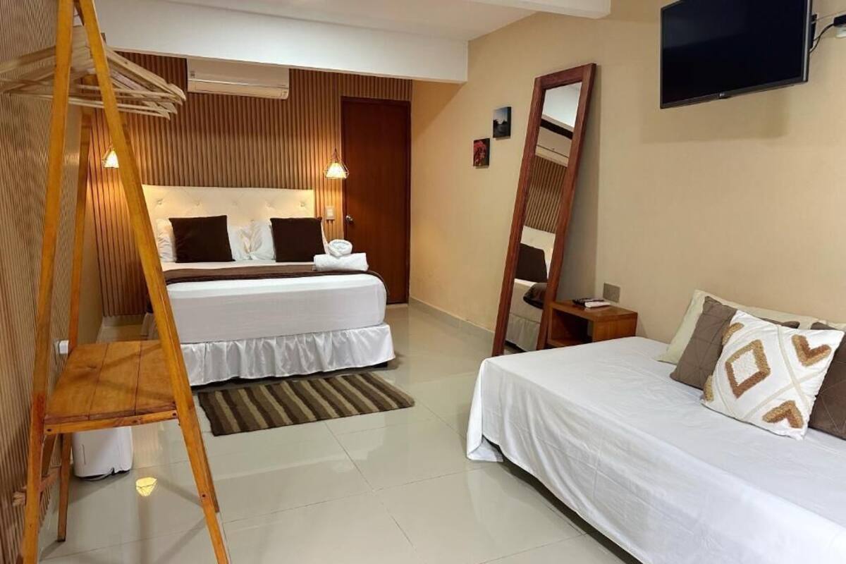 Habitación de hotel con dos camas, una escalera de madera, un televisor y un espejo.