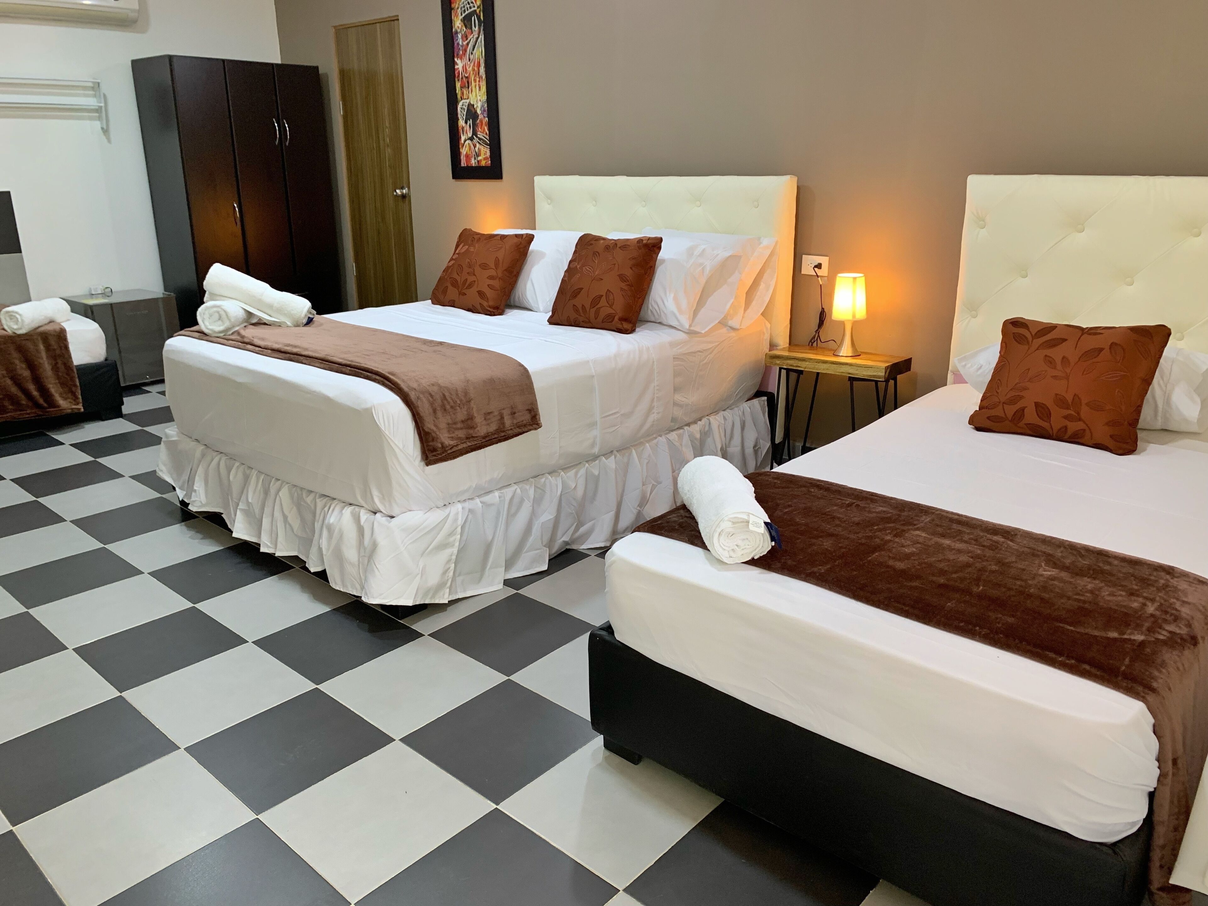 Habitación de hotel con dos camas, piso a cuadros y un cuadro en la pared.