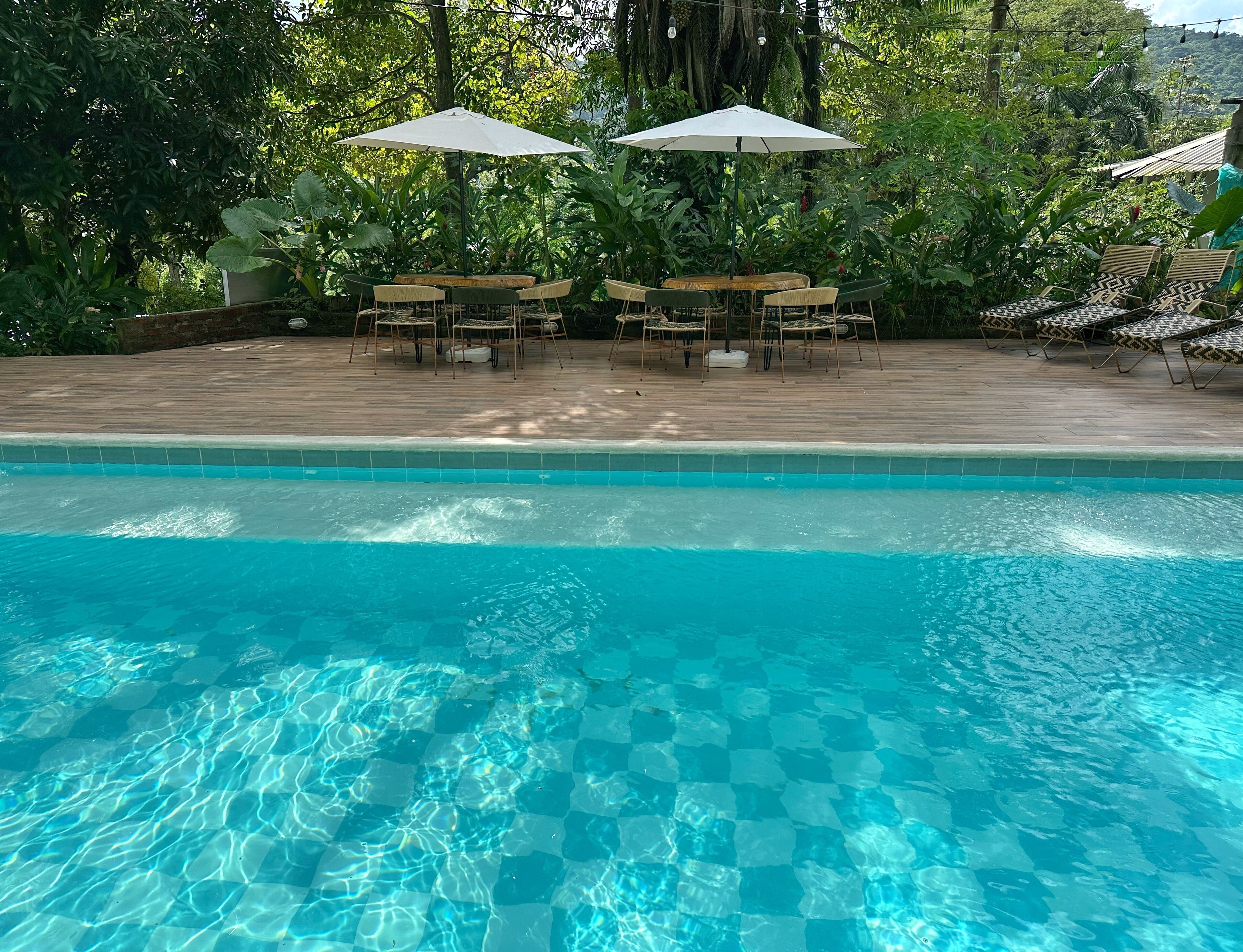 Piscina cristalina con cubierta de madera y zona de estar al aire libre.