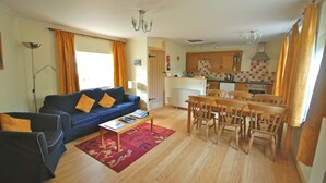 A compact living space with a sofa, coffee table, dining table, and chairs. - Hydrangea Cottage, Detached 1750,s Stone Cottage, Fully Modernised (Taynuilt)