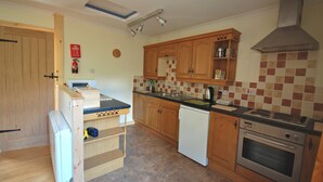 A kitchen with wooden cabinets, a dishwasher, a stove, and a tiled backsplash. - Hydrangea Cottage, Detached 1750,s Stone Cottage, Fully Modernised (Taynuilt)