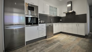 Una cocina moderna con electrodomésticos de acero inoxidable, armarios blancos y un suelo con patrón de espiga.