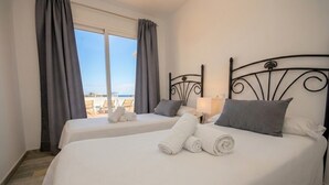 Habitación de hotel con dos camas, vista al mar y un balcón.