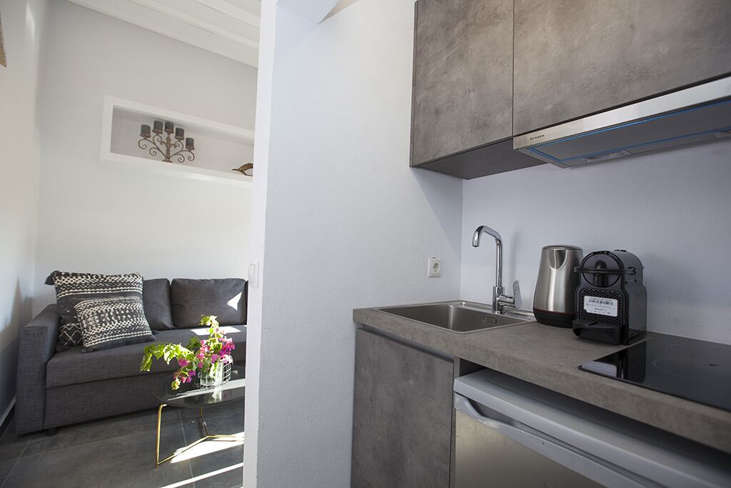 A modern kitchen with a built-in dishwasher, a coffee maker, and a kettle on the countertop.