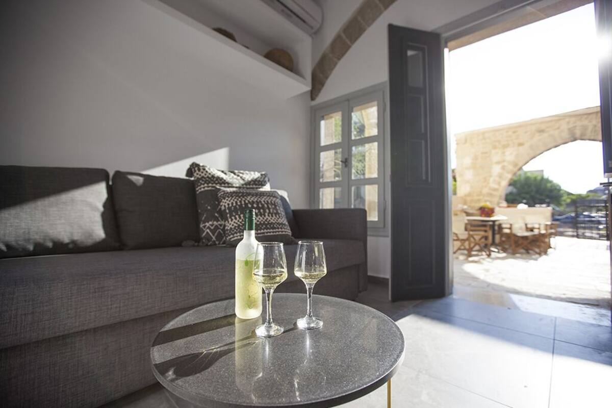 A modern living room with a round table, a sofa, and a wine bottle.