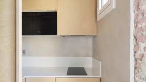 Une cuisine de taille réduite avec un lave-vaisselle noir, des meubles en bois et un plan de travail blanc.