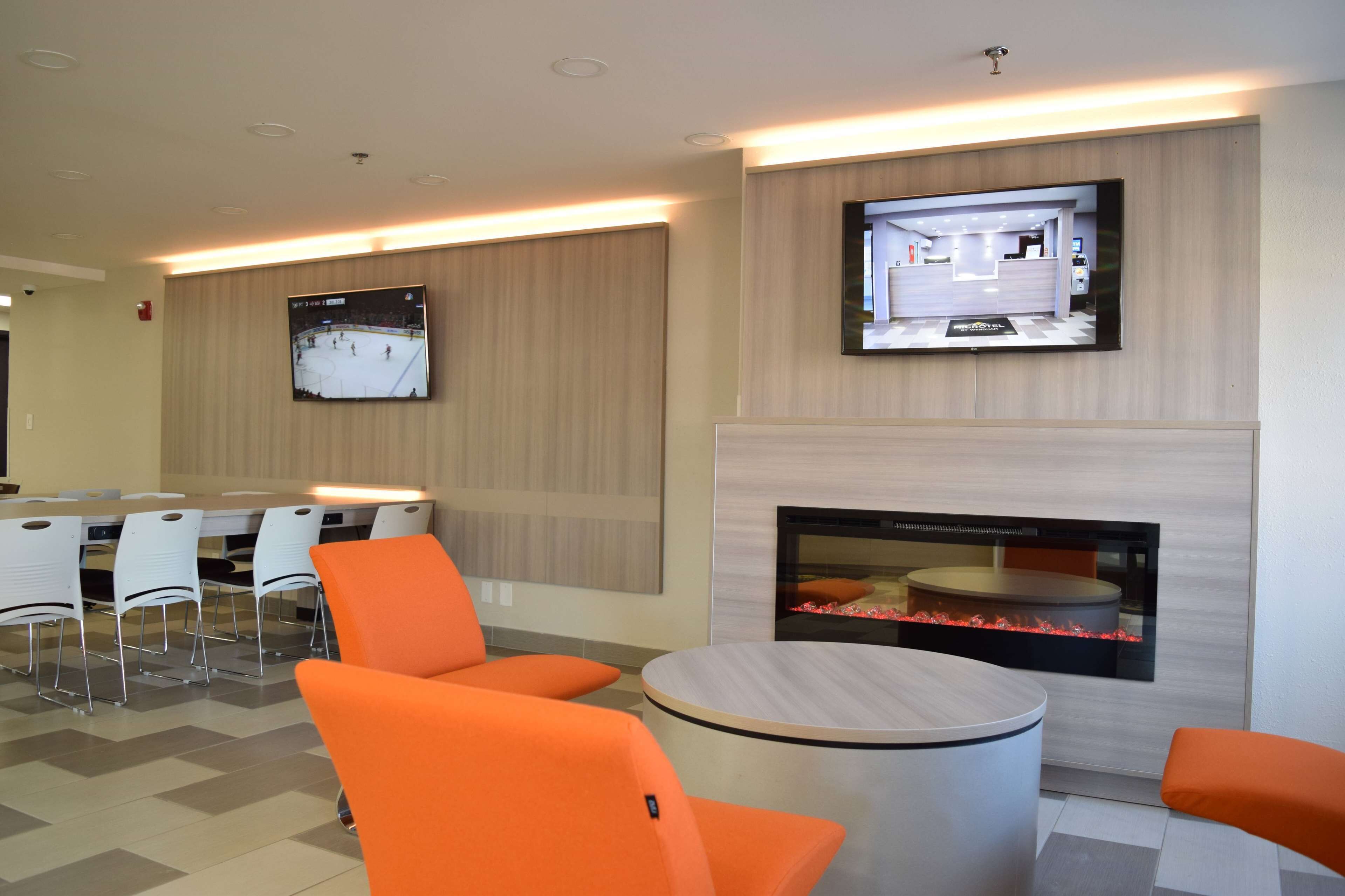 A modern lounge area with a flat-screen TV, a fireplace, and orange seating.