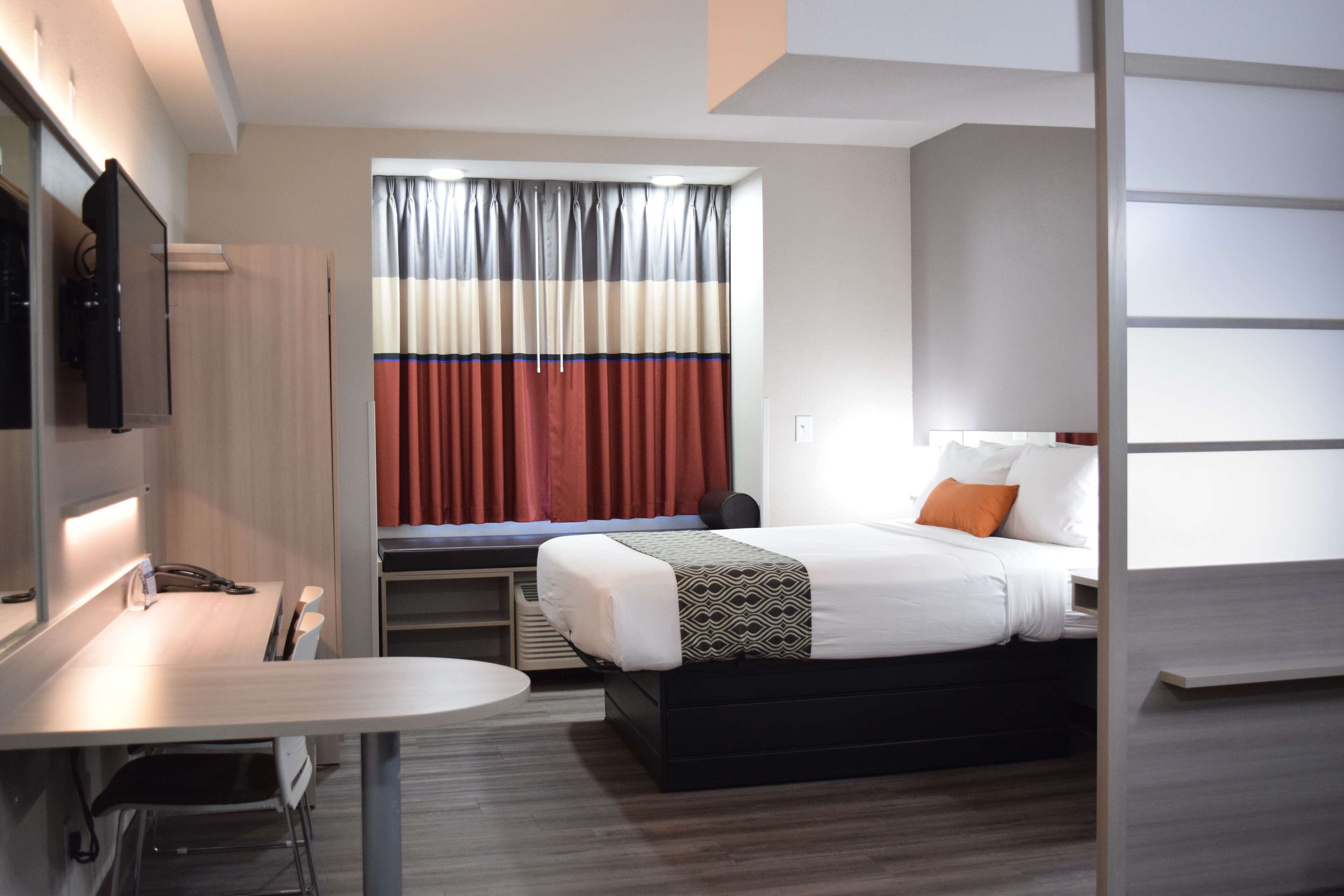 Una habitación de hotel moderna con una cama, una mesita de noche y un escritorio con una silla.