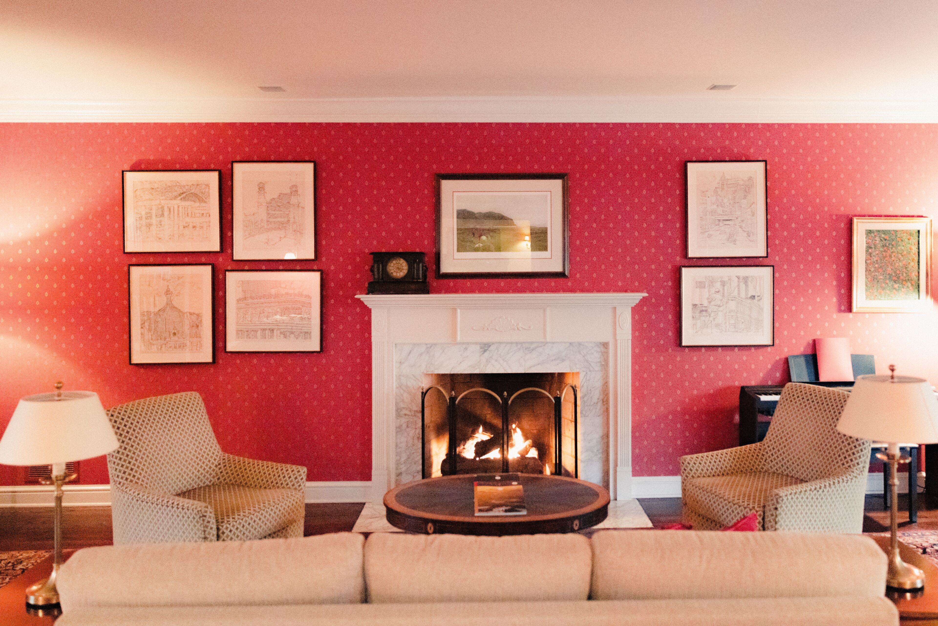 Una sala de estar con chimenea, dos sillones, un sofá y cuadros en la pared.
