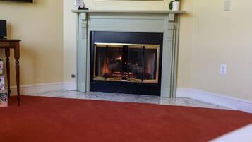 A fireplace with a fire, a television on a stand, and a red carpet.