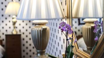 Une lampe dotée d’une surface réfléchissante et un vase orné de fleurs violettes.