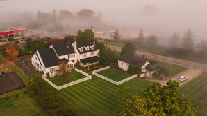 Une vue aérienne d’une grande maison avec une pelouse bien entretenue, une cour clôturée et une allée bien visible.
