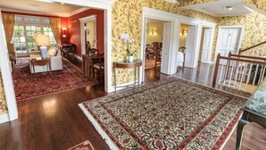 Un vaste espace de vie doté de planchers en bois, d’un grand tapis à motifs et d’un coin repas avec des chaises et une table.