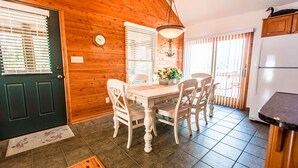 A wooden interior with a dining table, chairs, a clock, and a hanging light fixture. - Immaculate Family-Friendly Canal Front Vacation Home in Outer Banks 4x4 Area (Corolla)