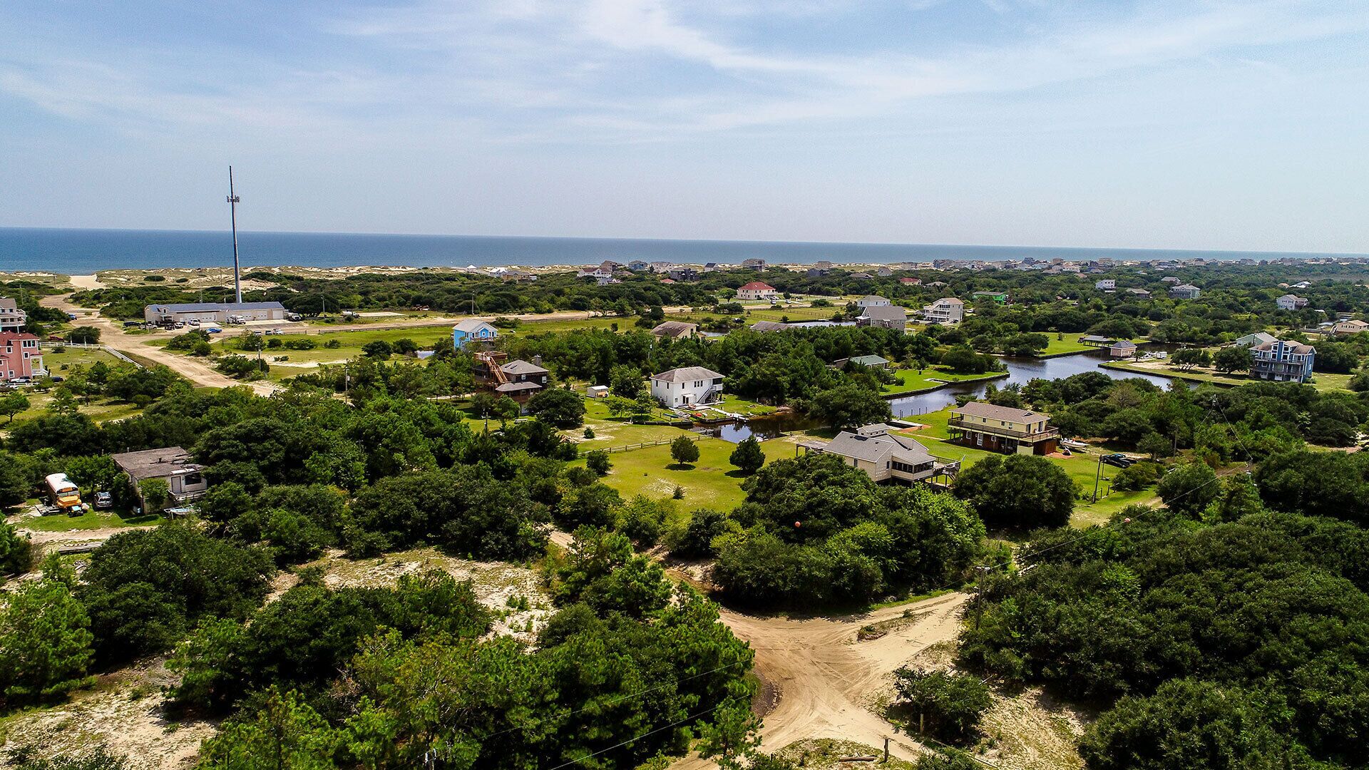 An aerial view of a residential area with houses, a body of water, and a large industrial building.