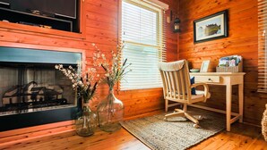 A cozy room with a fireplace, a wooden desk, and a chair. - Immaculate Family-Friendly Canal Front Vacation Home in Outer Banks 4x4 Area (Corolla)