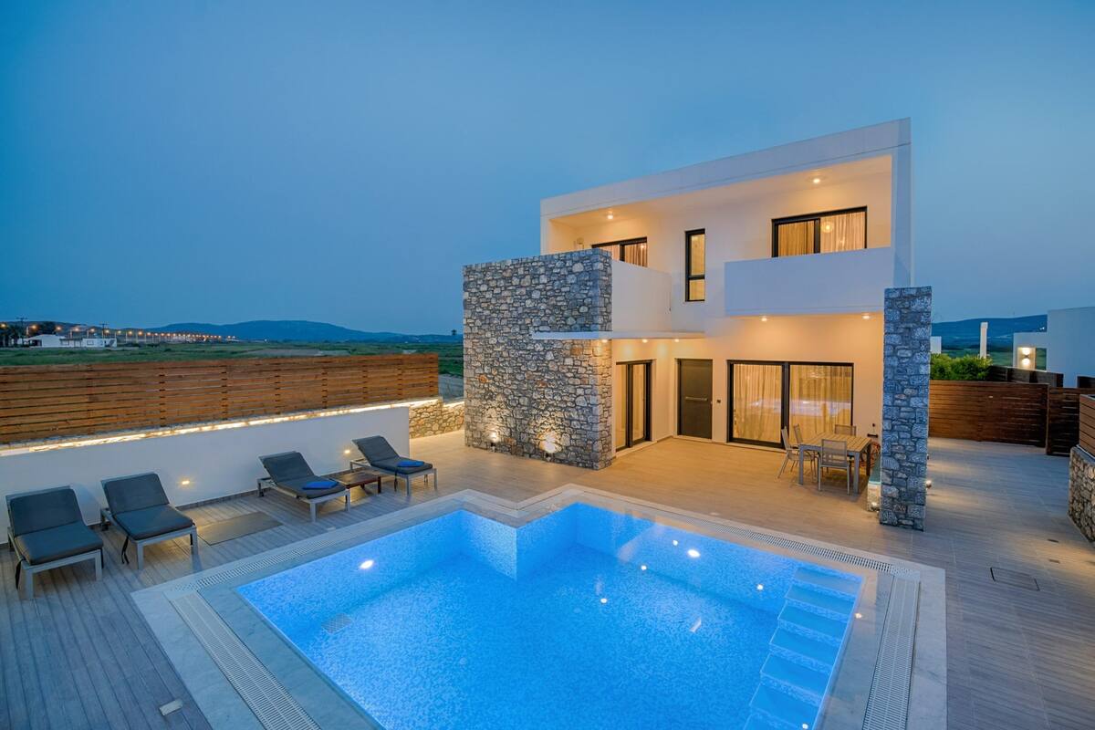 Una casa moderna de dos pisos con piscina, mobiliario exterior y fachada de piedra.