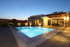 A swimming pool with a stone facade and a covered patio area. - Prasonisi Villas (Rhodes)