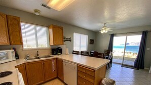 A kitchen with wooden cabinets, a dishwasher, a stove, and a trash can.