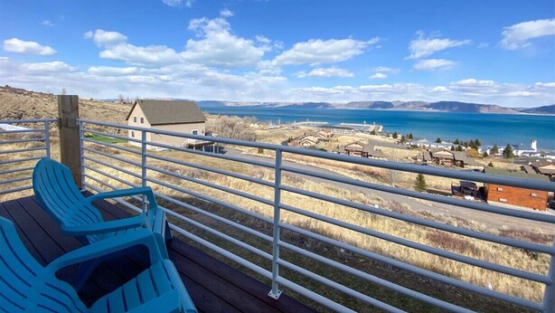 A deck with a view of a lake and distant mountains.