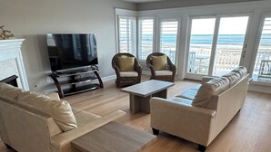 A spacious living room with a large TV, two sofas, a coffee table, and a fireplace. - Beautiful 5-bedroom 5-bathroom home on the Beach at the Jersey Shore (Point Pleasant Beach)