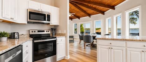 A modern kitchen with white cabinetry, stainless steel appliances, and a wooden ceiling.