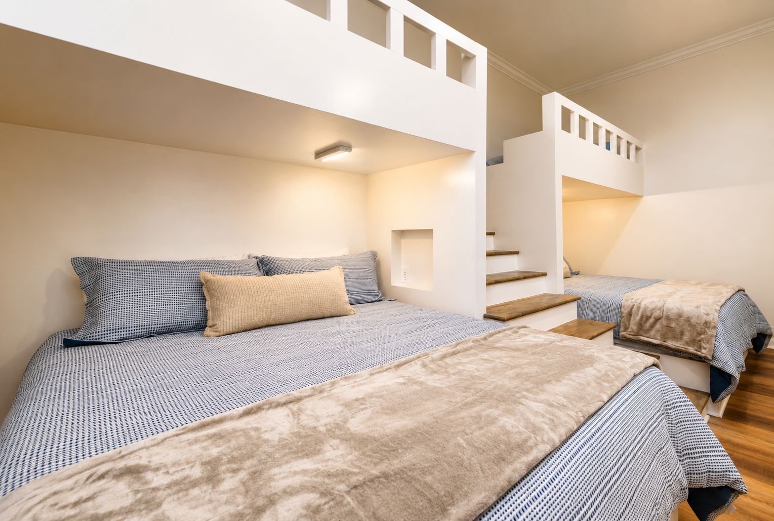 Une chambre avec deux lits, un escalier et un luminaire.
