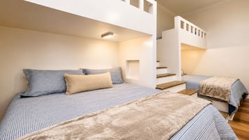 A bedroom with two beds, a staircase, and a light fixture.