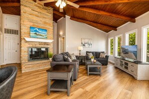A living room with a stone fireplace, two sofas, a coffee table, and a television.