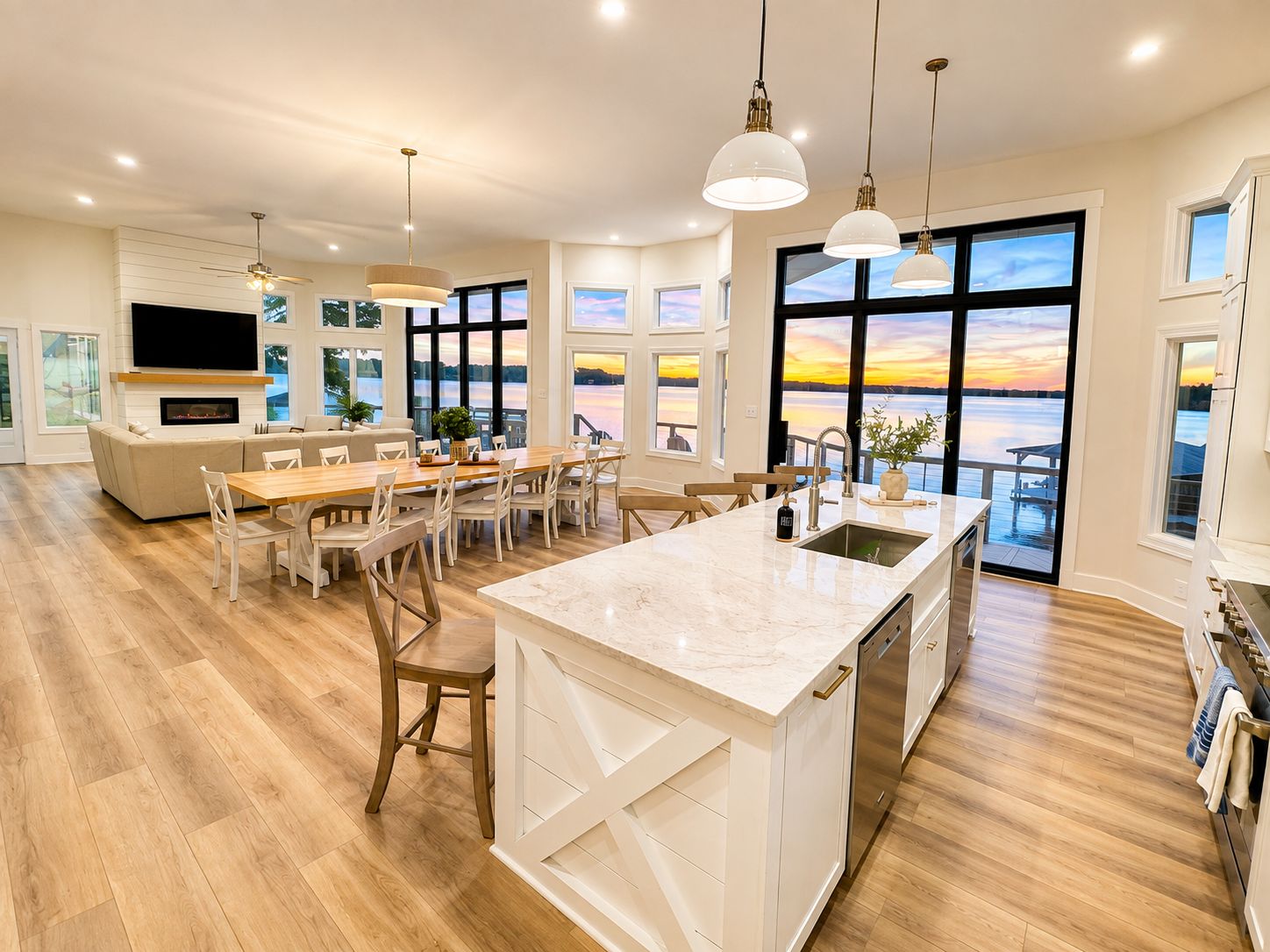Une cuisine moderne dotée d’un grand îlot central, de planchers en bois et de grandes fenêtres offrant une vue sur l’extérieur.