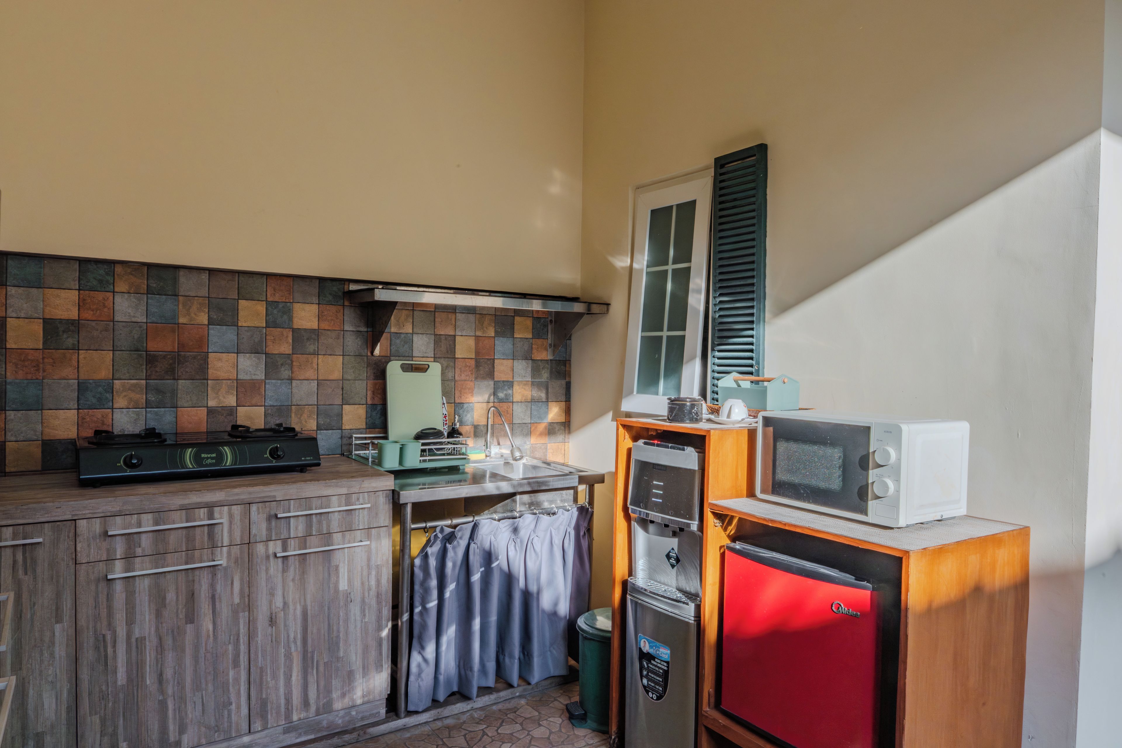 A compact kitchen with a gas stove, a microwave, and a small refrigerator.