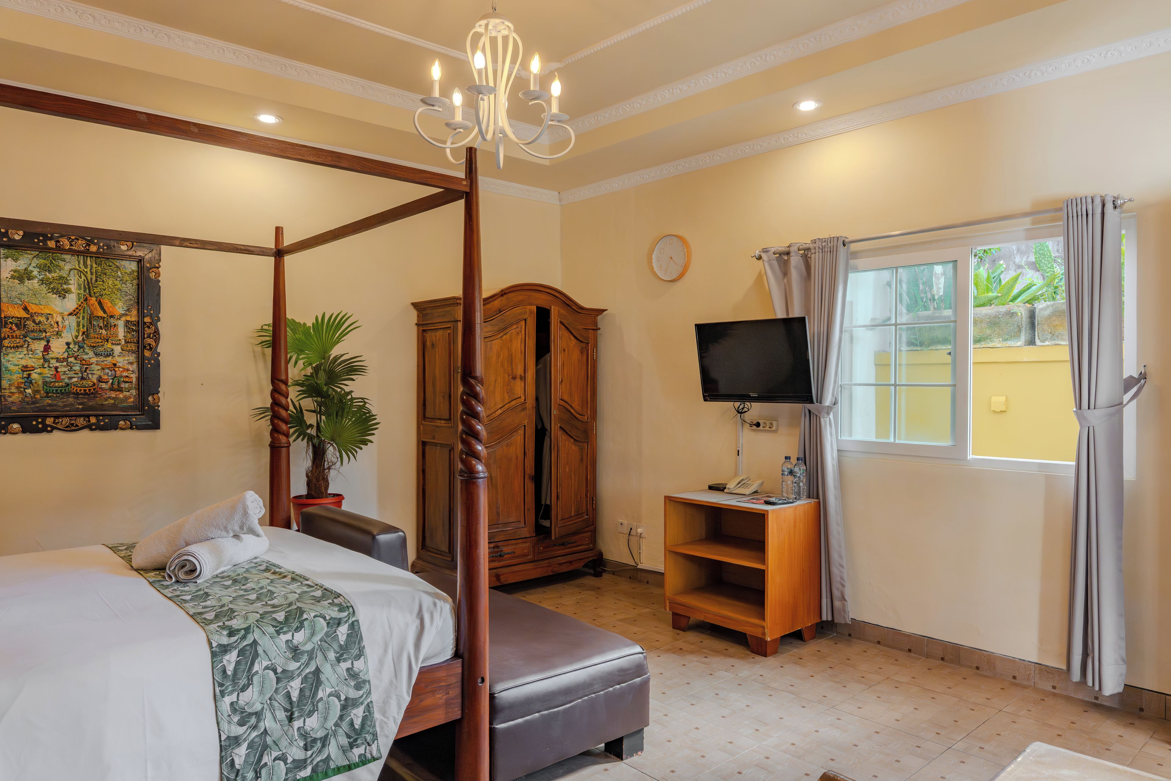 Une chambre à coucher avec un lit à baldaquin, une télévision, une horloge et une fenêtre avec des rideaux.