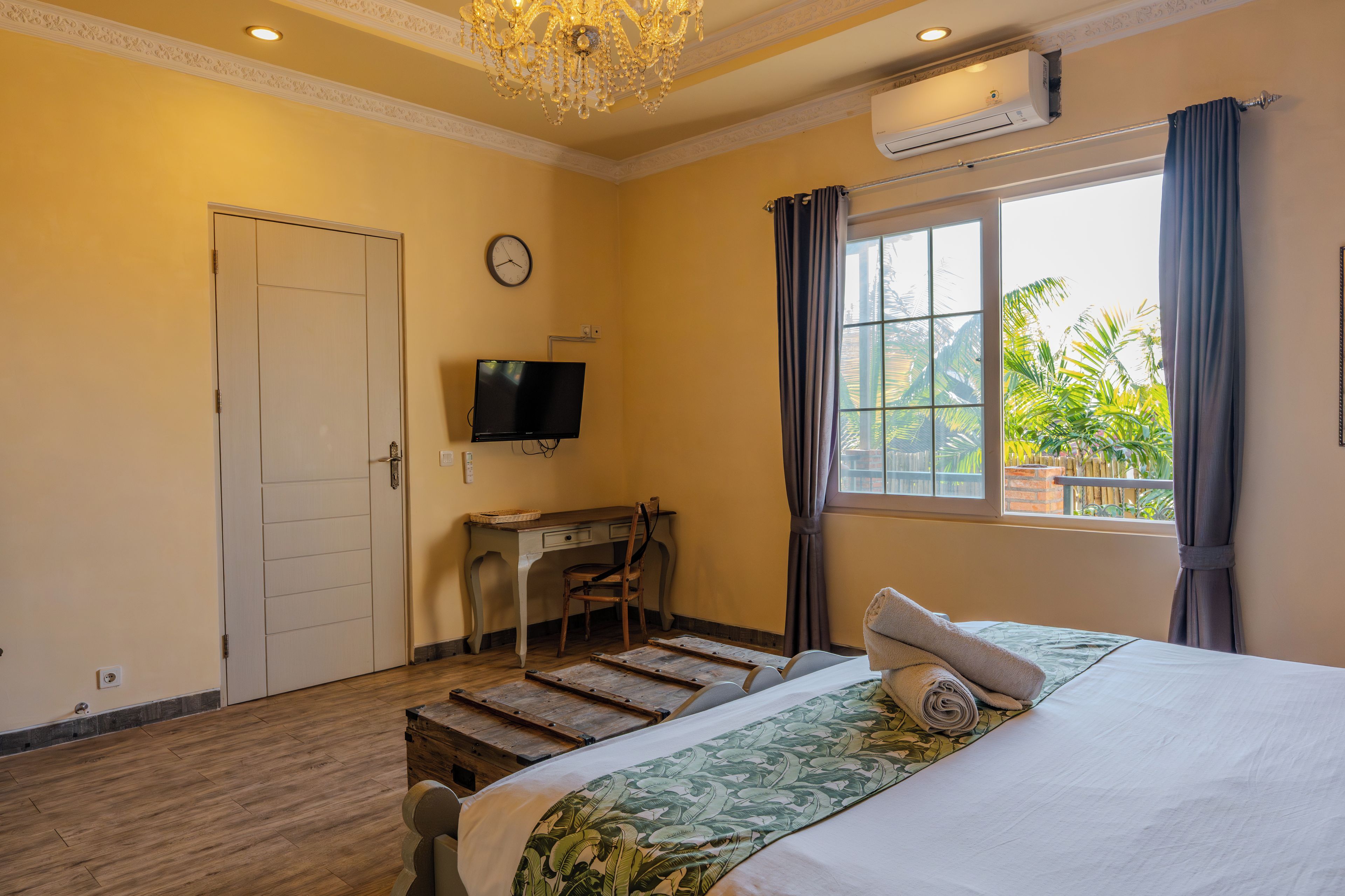 Una habitación de hotel con una cama, un escritorio, un televisor y una ventana con cortinas.