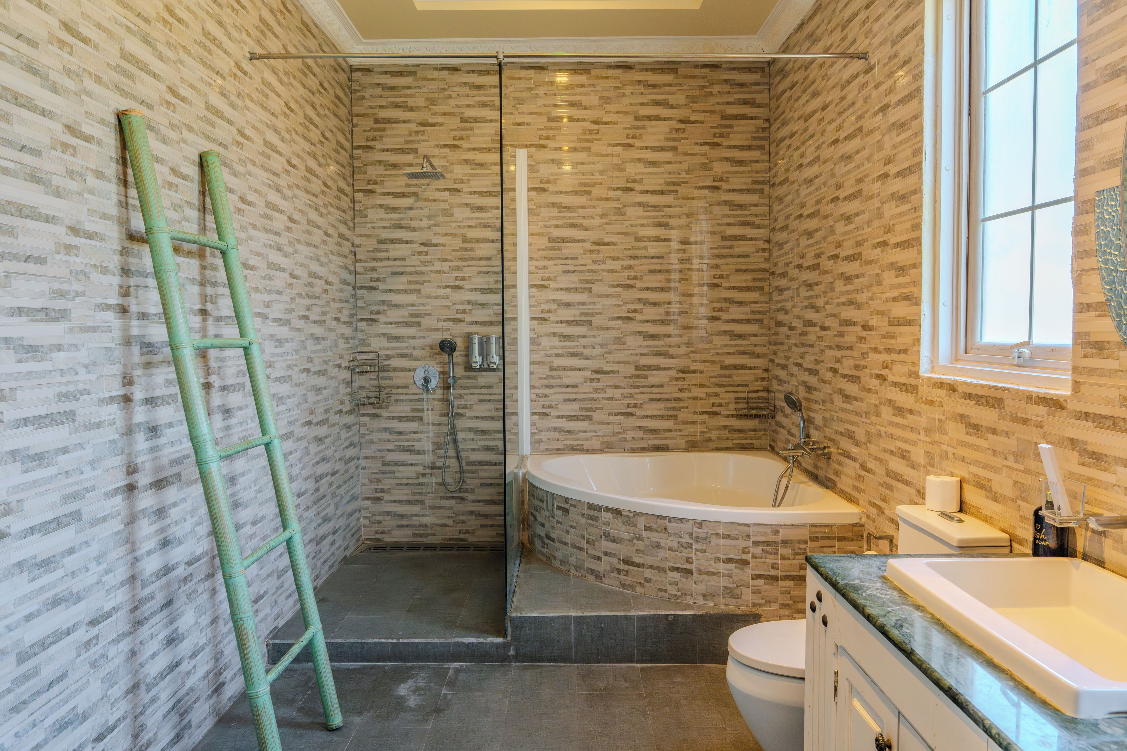 A bathroom with a glass-enclosed shower, a bathtub, and a toilet.