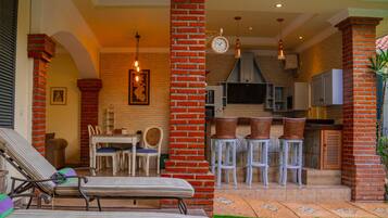 Suite de dos dormitorios con piscina, tumbonas en la terraza y zona de cocina.