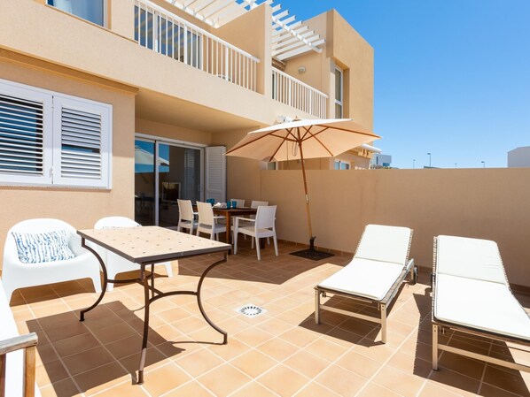 An outdoor patio with a table, chairs, and a sun umbrella. - Beautiful sea view duplex - PORÍS 1 (Poris de Abona)
