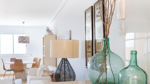 A modern living room with a dining area, featuring a table, chairs, a lamp, and decorative vases. - Beautiful sea view duplex - PORÍS 1 (Poris de Abona)
