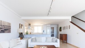 A modern living room with a white sofa, a wooden coffee table, and a kitchen in the background. - Beautiful sea view duplex - PORÍS 1 (Poris de Abona)