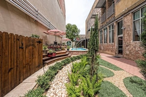 Relax in a serene courtyard with a paved pathway, seating area, and lush garden.