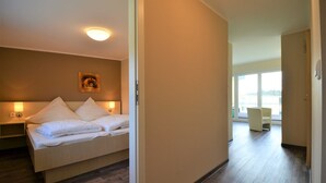 A hotel room with a bed, bedside table, and a painting on the wall.