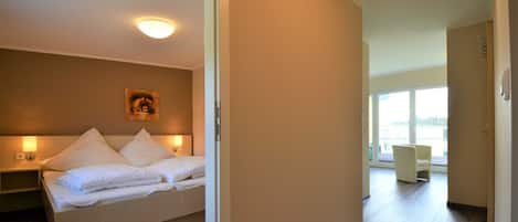 A hotel room with a bed, bedside table, and a painting on the wall.