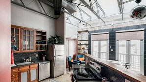A modern kitchen with wooden cabinets, a stainless steel refrigerator, and a large window overlooking a balcony. - Green Door Lofts-Retro Loft - Silos/Downtown (Waco)