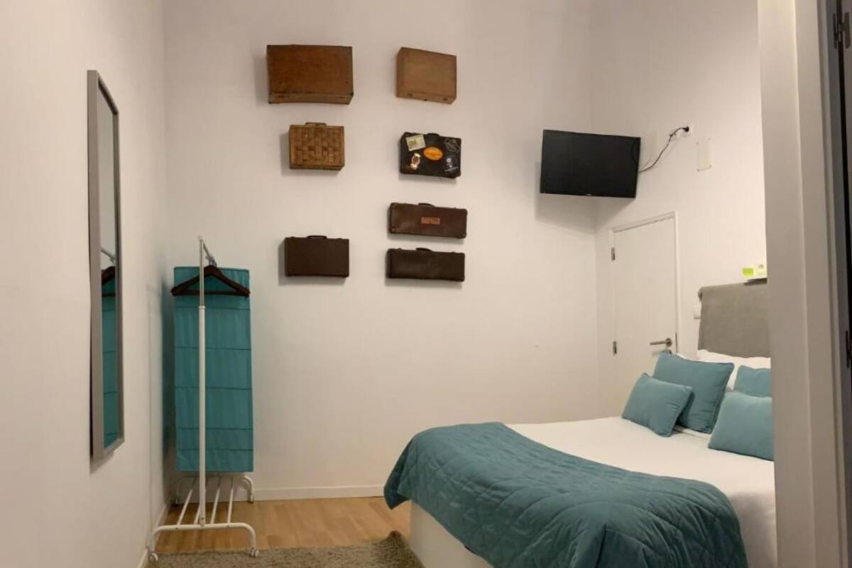 Un dormitorio con una cama, un televisor y un televisor montado en la pared.