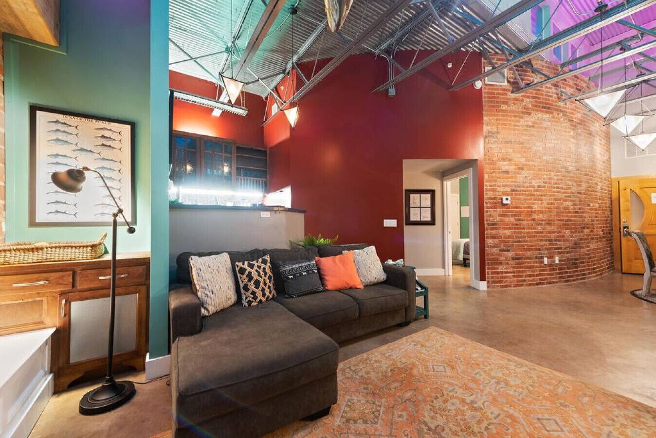 A modern living room with a sectional sofa, a desk, and a large rug.