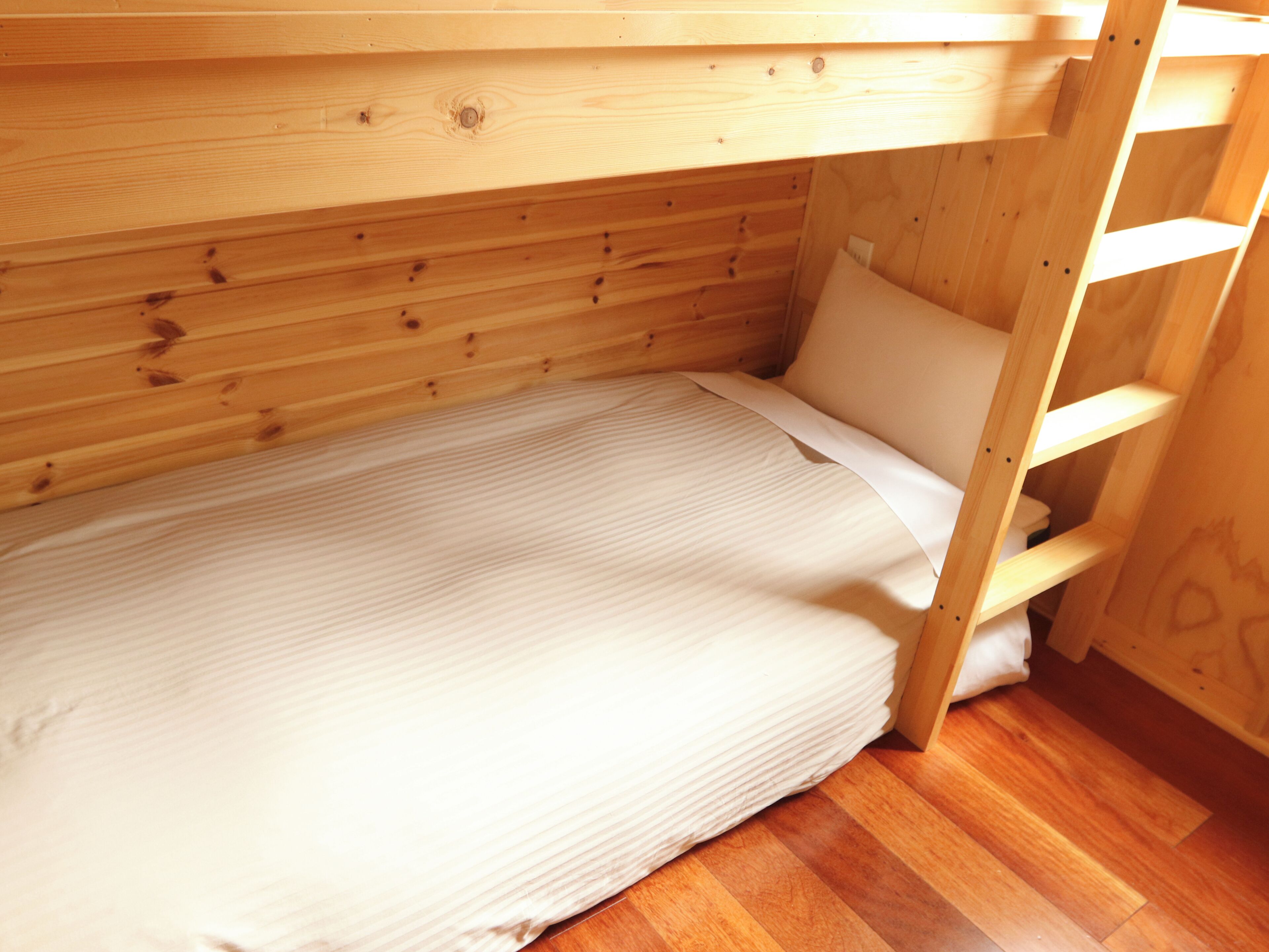 A bunk bed with a wooden frame and a white mattress.