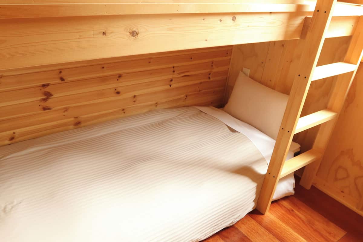 Una cama individual con estructura de madera y colchón blanco.