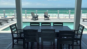 Ein überdachter Außenbereich mit Pooltisch, Stühlen und Blick auf den Ozean.