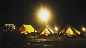 A row of tents illuminated by a single bright light source, likely a street lamp, with no visible windows or doors.
