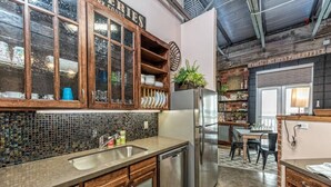 A kitchen with wooden cabinets, a stainless steel refrigerator, and a tiled backsplash. - Green Door Lofts -Magnolia Loft, Silos/Downtown (Waco)