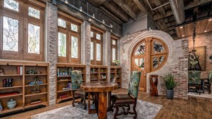 Une bibliothèque avec des étagères en bois, une table ronde en bois et un mur en pierre.